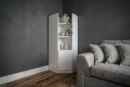Meuble d'angle blanc mat dans un salon aux murs sombres pour agrandir visuellement l'espace