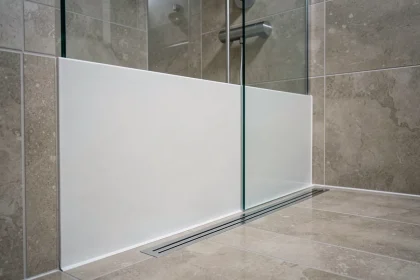 Plaque PVC blanche installée dans une douche italienne moderne avec drain linéaire et paroi en verre